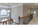 Upstairs hallway with wood and iron railing and natural light from arched window at 3835 Greenside Ct, Dacula, GA 30019