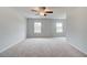 Spacious bedroom featuring neutral carpet, light walls, a ceiling fan, and two bright windows at 324 Shine Dr, Stockbridge, GA 30281
