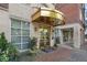 Elegant building entrance with a golden awning, glass doors, and lush planters at 77 Peachtree Ne Pl # 402, Atlanta, GA 30309