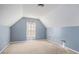 Finished attic bedroom features neutral carpet and light blue painted walls, with light pouring in from one window at 1115 Harvest Brook Ne Way, Lawrenceville, GA 30043