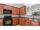 Kitchen with wooden cabinets, tile backsplash, and black appliances, and a stainless steel sink at 1115 Harvest Brook Ne Way, Lawrenceville, GA 30043