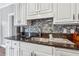 Close-up of a kitchen featuring dark granite countertops, a mosaic backsplash, and modern appliances at 3207 Haleys Way, Conyers, GA 30013