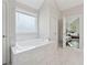 Bright bathroom with tub, large window, marble floors, and an open doorway to the bedroom at 8023 White Stone Blvd, Douglasville, GA 30135