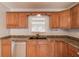 Close-up of the kitchen sink area with wood cabinets and stainless steel dishwasher at 3625 Knoll Crest Trl, Buford, GA 30519