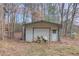 Backyard storage shed with garage door and riding lawn mower in the yard at 3625 Knoll Crest Trl, Buford, GA 30519