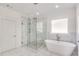 Bright bathroom featuring a glass shower with marble tile and a modern soaking tub by the window at 603 Old Peachtree Ne Rd, Lawrenceville, GA 30043