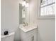 Compact bathroom featuring white vanity with stone countertop, a modern faucet, and ample lighting from the window at 603 Old Peachtree Ne Rd, Lawrenceville, GA 30043