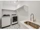 Bright laundry room with modern washer and dryer, a sink, and stylish tile flooring, offering a clean and functional space at 603 Old Peachtree Ne Rd, Lawrenceville, GA 30043