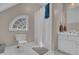 Well-lit bathroom featuring a tub and shower combo, toilet, vanity, and an arched window at 1421 Hedgewood Nw Ln, Kennesaw, GA 30152