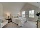 Bright bedroom featuring a tufted headboard, plush bedding, and abundant natural light from two large windows at 1856 Kingsmere Run Dr, Loganville, GA 30052