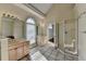 Bright bathroom featuring a double vanity, glass shower, and arched window at 1921 Harvest Way, Loganville, GA 30052