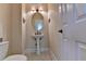 Charming powder room featuring a pedestal sink, decorative mirror, and elegant sconce lighting at 1921 Harvest Way, Loganville, GA 30052