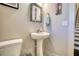 Stylish powder room with pedestal sink, decorative mirror, and adjacent staircase at 5114 Arnold St, Covington, GA 30014