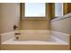 Relaxing bathtub area featuring a soaking tub and a window for natural light at 5114 Arnold St, Covington, GA 30014