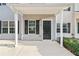 Inviting entrance with a covered porch, a black door with a matching storm door, and manicured landscaping at 129 Prospect Path, Hiram, GA 30141