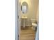 This half bathroom features wood floors, a pedestal sink, oval mirror, and standard toilet at 1847 Kingsmere Run Dr, Loganville, GA 30052