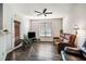 Living room featuring dark wood floors, a ceiling fan, a large window, and comfortable leather furniture at 11358 Michelle Way, Hampton, GA 30228