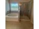Bright bathroom features a soaking tub under a window and a glass-door walk-in shower at 1857 Kingsmere Run Dr, Loganville, GA 30052
