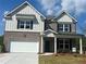 Charming two-story home featuring a brick and board-and-batten facade, black shutters, and a two-car garage at 1857 Kingsmere Run Dr, Loganville, GA 30052