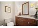 A half bathroom with a white countertop, mirror, sconces, toilet, wood cabinets, and neutral paint is displayed at 3630 Peachtree Ne Rd # 1809, Atlanta, GA 30326