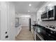 Well-lit kitchen with stainless steel appliances, white cabinets and black countertops at 6058 Ledgewood Dr, Forest Park, GA 30297