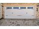 White two-car garage door with carriage style hardware, and brick surround at 495 Duval Dr, Alpharetta, GA 30009