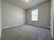 A carpeted bedroom with a window for natural light and an entrance door at 1327 Fern Ridge Ct # 27, Norcross, GA 30093