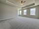 A large carpeted main bedroom features a tray ceiling, fan and two windows at 1327 Fern Ridge Ct # 27, Norcross, GA 30093