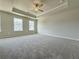 A large carpeted main bedroom features a tray ceiling, a fan, and two windows at 1327 Fern Ridge Ct # 27, Norcross, GA 30093