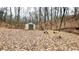 A storage shed with a stone bench and bird bath in a wooded, leaf-covered area, perfect for outdoor relaxation at 7460 Highway 101, Rockmart, GA 30153