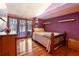 Bright bedroom with hardwood floors, a decorative bed frame, a window with curtains, and light purple walls at 2513 Overlake Ln, Stockbridge, GA 30281