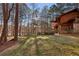 Lawn leading to wooded home featuring a wall of windows with views of the lake at 2513 Overlake Ln, Stockbridge, GA 30281