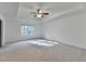 Bright primary bedroom with tray ceiling and a ceiling fan, showcasing a spacious layout and natural light from the window at 4118 Haleston Rd, Duluth, GA 30097