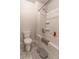 Bathroom showcasing a toilet and bathtub-shower combination with white tiling and storage shelves at 4480 Sunflower Cir, Cumming, GA 30040