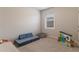 A serene bedroom featuring plush carpet, a cozy blue sofa, and a bright, sunny window at 4480 Sunflower Cir, Cumming, GA 30040