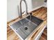 Close up of a new stainless steel kitchen sink with modern faucet and butcher block countertop at 2413 Charleston Pointe Ct, Atlanta, GA 30316
