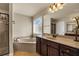 Well-appointed bathroom featuring a soaking tub, granite countertops, a large mirror, and decorative lighting at 2468 Cannon Farm Ln, Duluth, GA 30097