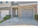 Townhome entrance with a stone facade, gray garage door, and a covered porch at 5036 Longview Walk, Decatur, GA 30035