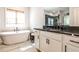 This bright bathroom offers a soaking tub and white cabinets with a contrasting black marble countertop and modern hardware at 108 Fieldbrook Xing, Holly Springs, GA 30115