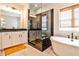 This modern bathroom features a glass shower, soaking tub, and double vanity sink with dark granite countertop at 108 Fieldbrook Xing, Holly Springs, GA 30115