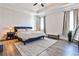 A spacious main bedroom features wood floors, a tray ceiling, and lots of natural light from the two large windows at 108 Fieldbrook Xing, Holly Springs, GA 30115