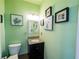 Charming half bathroom featuring green walls, decorative art, a vanity and toilet at 3170 Wood Springs Sw Trce, Lilburn, GA 30047