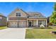 Exterior elevation view of charming home showcasing a stone and siding facade and a two-car garage at 145 Meadow Branch Ln, Dallas, GA 30157