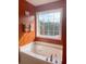 Bathroom featuring a soaking tub, large window, and orange walls at 7235 Magnolia Ln, Fairburn, GA 30213