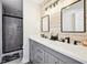 Modern bathroom featuring double sinks, matte black fixtures, a stylish wood accent wall, and glass shower at 8 Pine Canyon Sw Dr, Atlanta, GA 30331