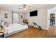 A brightly lit bedroom features a ceiling fan, a TV, wood flooring, and a glimpse into an adjacent room at 1042 Wedgewood Ct, Conyers, GA 30012