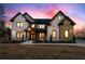Striking two-story brick home with stone accents is beautifully lit at dusk in the evening at 1798 Braselton Hwy, Lawrenceville, GA 30043