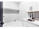 Clean laundry room with white cabinetry, modern sink, and marble tile flooring at 1798 Braselton Hwy, Lawrenceville, GA 30043