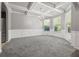 Elegant living area with coffered ceilings, large windows, and white trimwork detail with gray carpeting at 5253 Rosewood Pl, Fairburn, GA 30213
