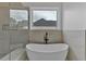 Bathroom featuring a freestanding tub beneath a window, with tiled walls and a glass-enclosed shower nearby at 3286 Elwin Ragsdale Way, Acworth, GA 30102